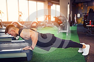 Young athletic man doing push-ups in gym. Muscular and strong gu