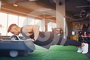 Young athletic man doing push-ups in gym. Muscular and strong gu