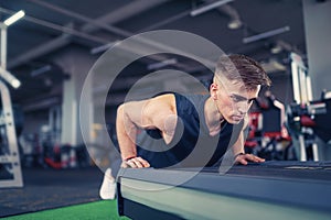 Young athletic man doing push-ups in gym. Muscular and strong guy exercising.