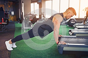 Young athletic man doing push-ups in gym. Muscular and strong guy exercising.