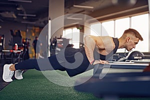 Young athletic man doing push-ups in gym. Muscular and strong guy exercising.
