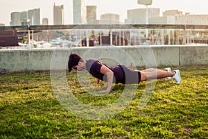 Young athletic man doing pushups exercises at park