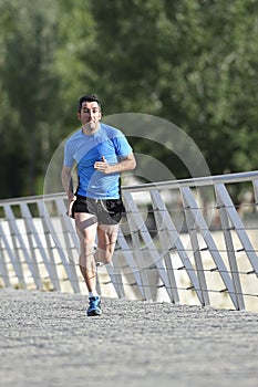 Young athletic man practicing running and sprinting on urban city park background in sport training