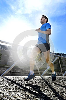 Young athletic man practicing running in urban background backlight in fitness sport training and healthy lifestyle concept