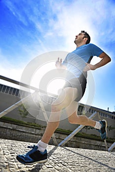 Young athletic man practicing running in urban background backlight in fitness sport training and healthy lifestyle concept