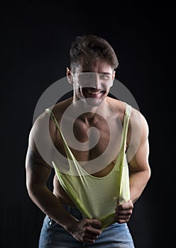 Young athletic man pulling down tanktop on ripped muscular torso