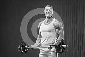 Young athletic man pumping up muscles in the gym at workout