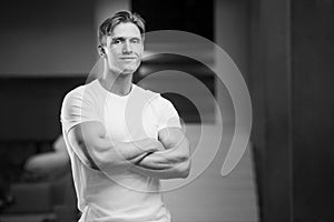 Young athletic man pumping up muscles in the gym at workout