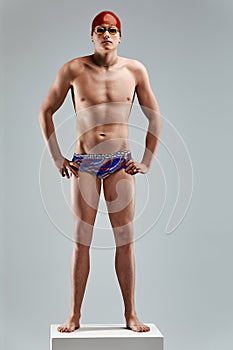 Young athletic man ready to jump into swimming pool against gray background. The concept of swimming and water games.