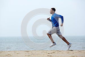 Young athletic man running at the beach