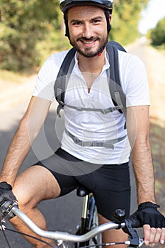 young athletic man standing with bicycle in colorful autumn park