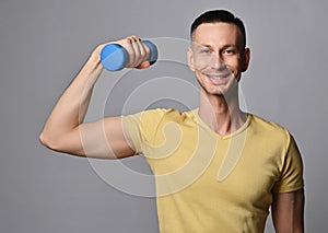 Young athletic man in t-shirt works out with weights, holds a dumbbell in hand. Healthy lifestyle