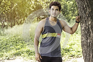 Young athletic man taking a break under tree during a challenging jogging outdoor .