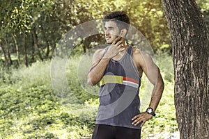 Young athletic man taking a break under tree during a challenging jogging outdoor .
