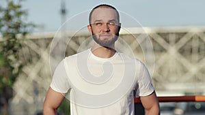 Young athletic man in white t-shirt doing warm up exercises outdoors