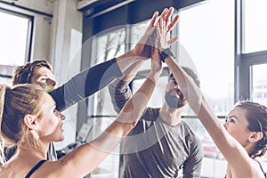 Young athletic people in sportswear giving high five in gym