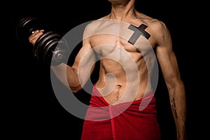 Young athletic shirtless man working out on black background photo