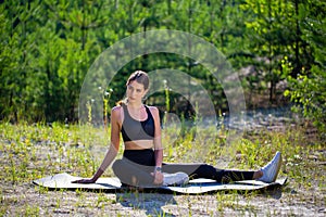 Young athletic slim girl in black leotard does gymnastics or yoga in the forest