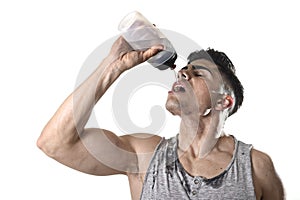 Young athletic sport man thirsty drinking water holding bottle pouring fluid on sweaty face