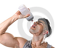 Young athletic sport man thirsty drinking water holding bottle pouring fluid on sweaty face