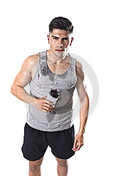 Young athletic sport man thirsty holding bottle of water with sweaty face and wet singlet