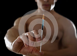 Young athletic sportsman holding syringe in sport doping and cheat concept