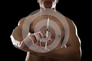 Young athletic sportsman holding syringe in sport doping and cheat concept