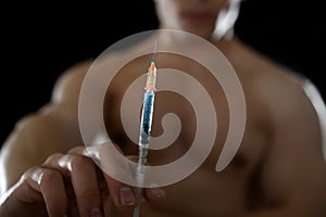 Young athletic sportsman holding syringe in sport doping and cheat concept
