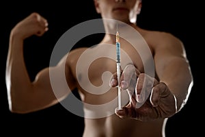 Young athletic sportsman holding syringe in sport doping and cheat concept