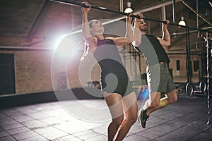 Young athletic sportspeople doing pull-ups in gym