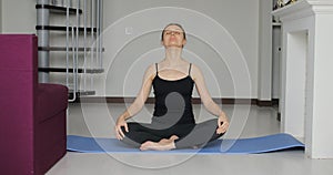 Young athletic sporty slim woman doing yoga exercise stretching her back on mat at home.