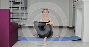 Young athletic sporty slim woman doing yoga exercise stretching her leg at home on mat