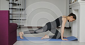 Young athletic sporty slim woman doing yoga exercise stretching her leg at home on mat.