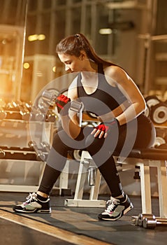 Young athletic woman doing exercises with dumbbells