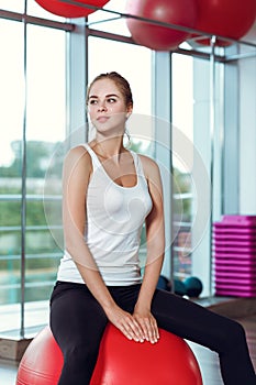 Young athletic woman doing exercises with fitness ball in gym