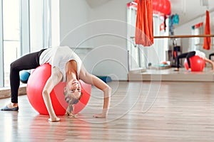 Young athletic woman doing exercises with fitness ball in gym