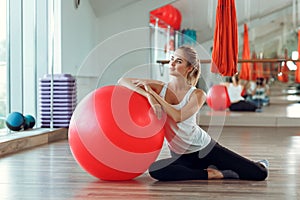 Young athletic woman doing exercises with fitness ball in gym