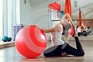 Young athletic woman doing exercises with fitness ball in gym