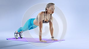 Young athletic woman doing plank. Muscular and strong girl exercising.