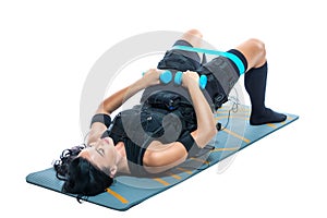 A young athletic woman in an EMS suit does an exercise on a dumbbell Mat on an isolated white background. EMS training