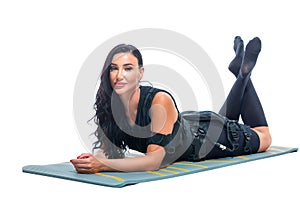 A young athletic woman in an EMS suit does lies on a Mat on an isolated white background. EMS training. Electrical