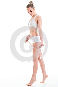 young athletic woman measuring waist measuring tape, isolated over white background