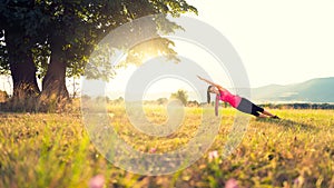 Young athletic woman practicing yoga on a meadow at sunset