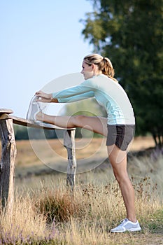 Young athletic woman stretches muscles after jogging, running and exercising outdoors in nature