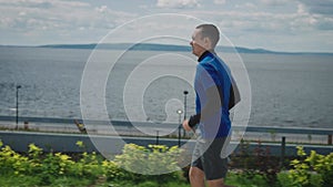 A young, athletically built young man runs along a well-maintained embankment. Workout to keep fit and feel good.