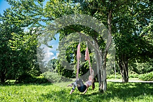 young athletically trained yoga trainer trains outdoors under a tree.