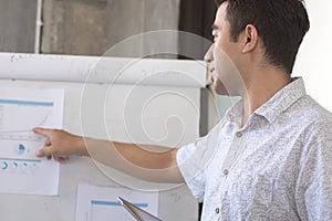 Young atractive asian man presenting graphic cart at white board