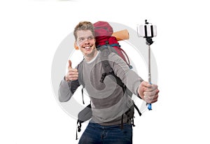 Young atractive traveler backpacker taking selfie photo with stick carrying backpack ready for adventure