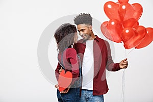 Young attactive African American couple holding heart balloon and paper.