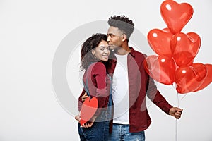 Young attactive African American couple holding heart balloon and paper.